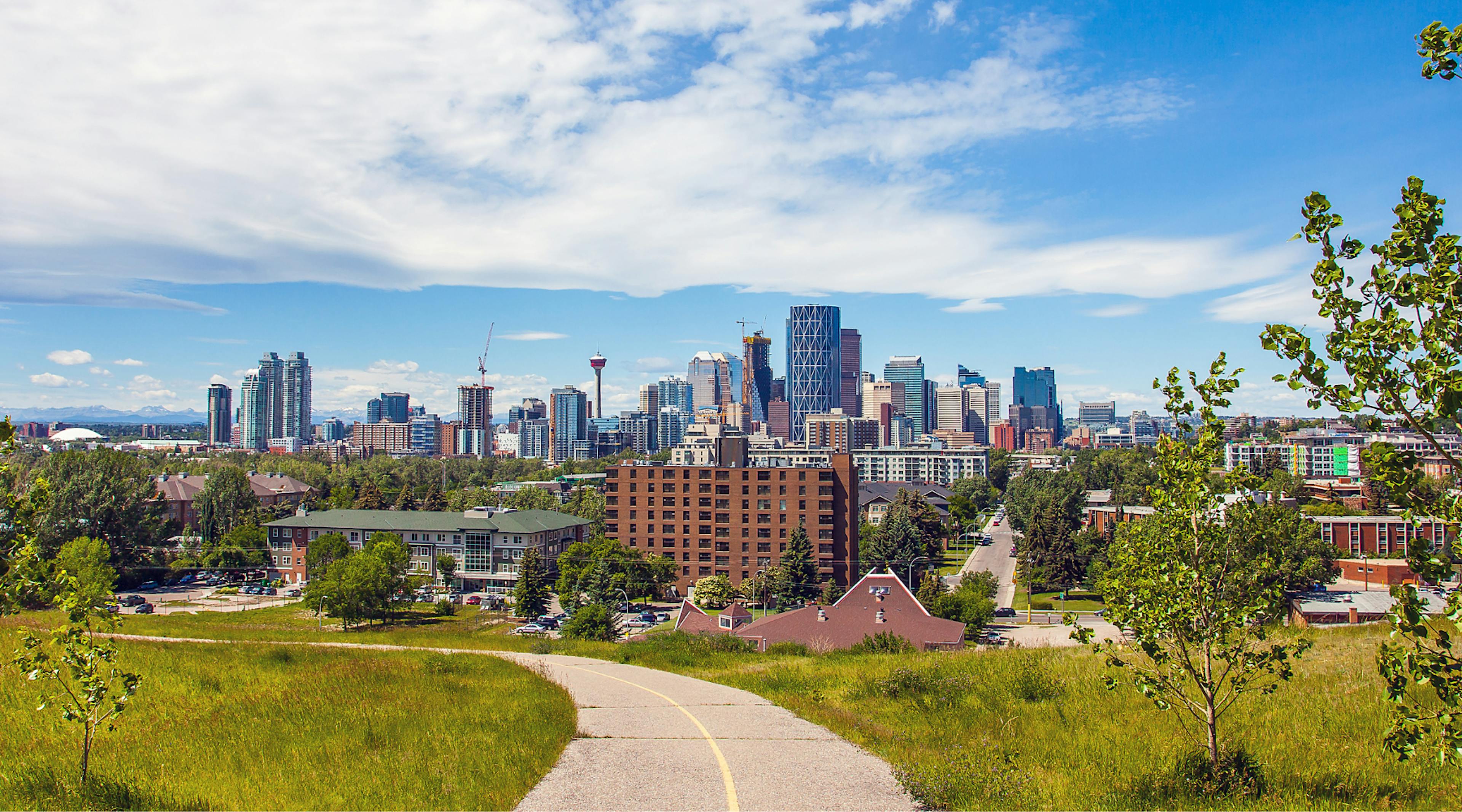 A path with trees and grass and Calgary's cityscape in the background