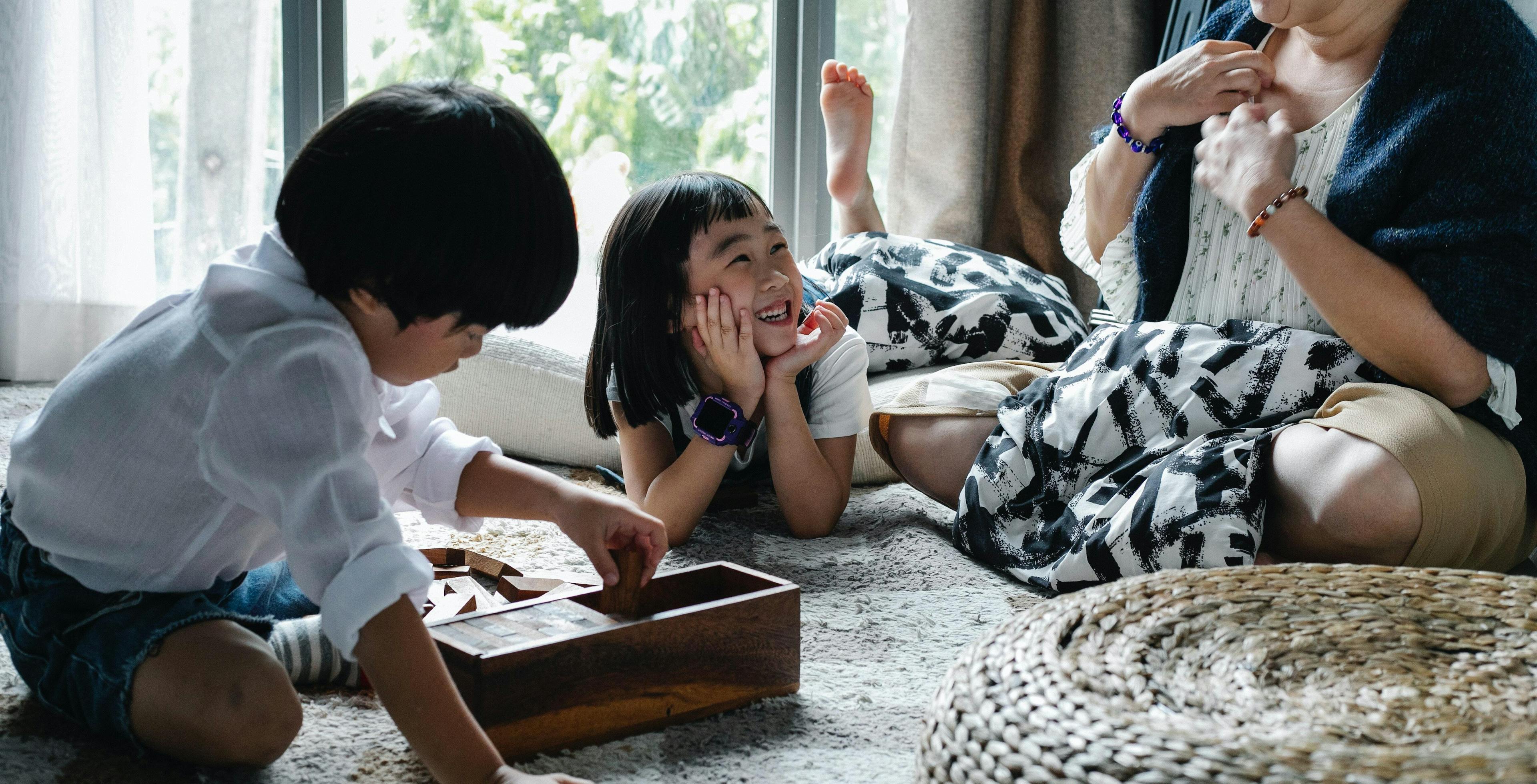 Children play in front of window with caregiver