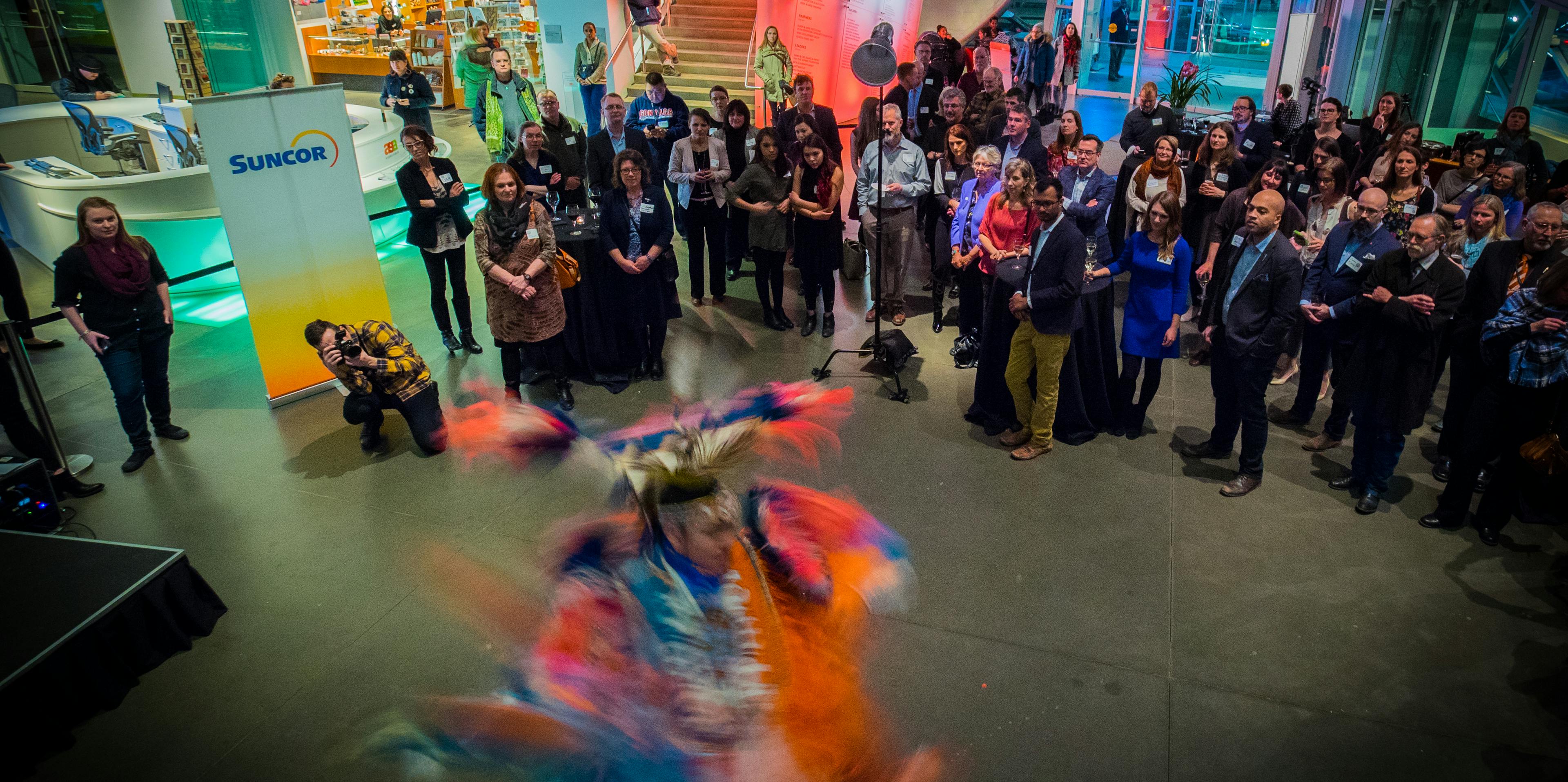 Room of people watch an Indigenous dancer