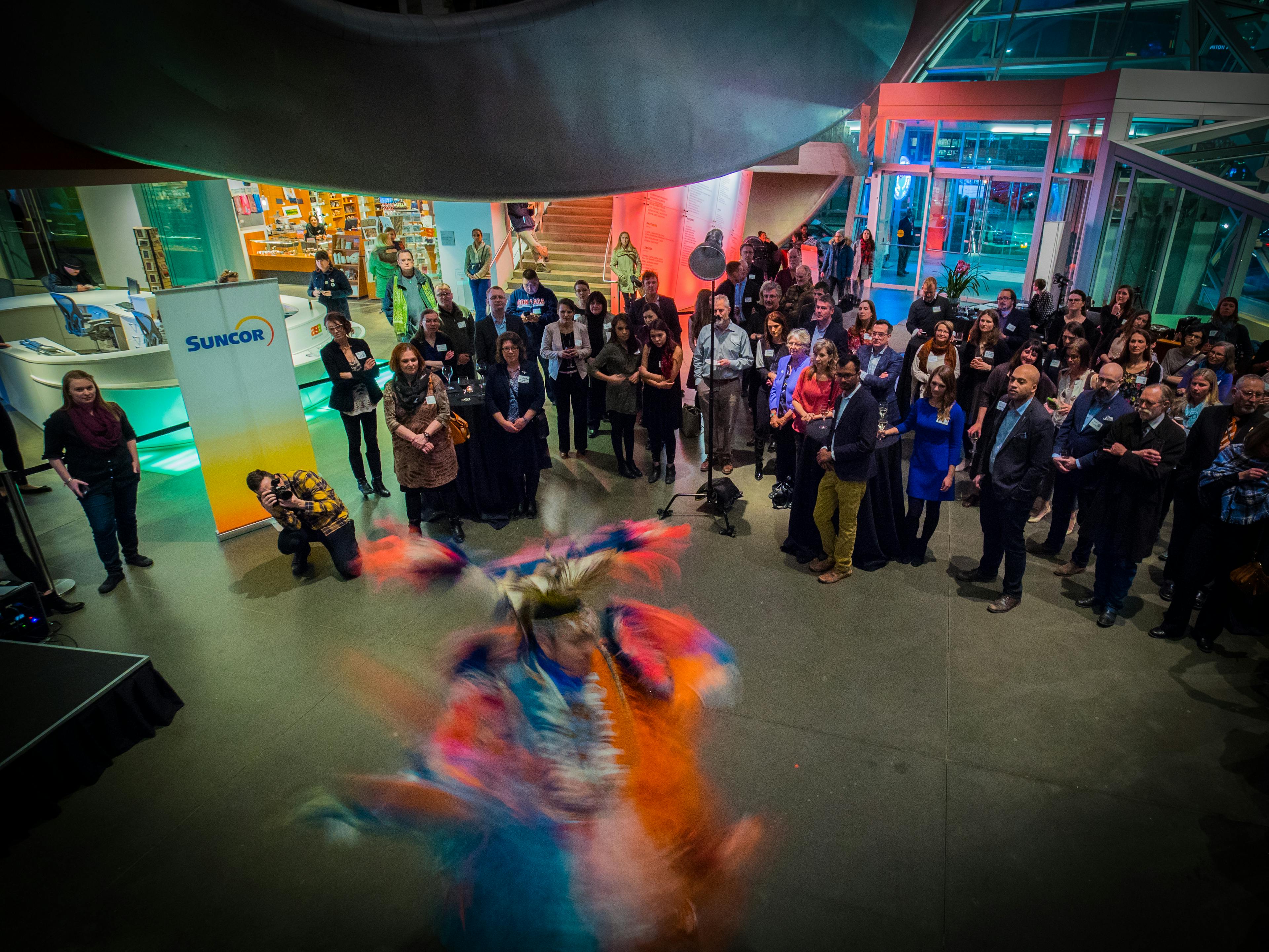 Room of people watch an Indigenous dancer