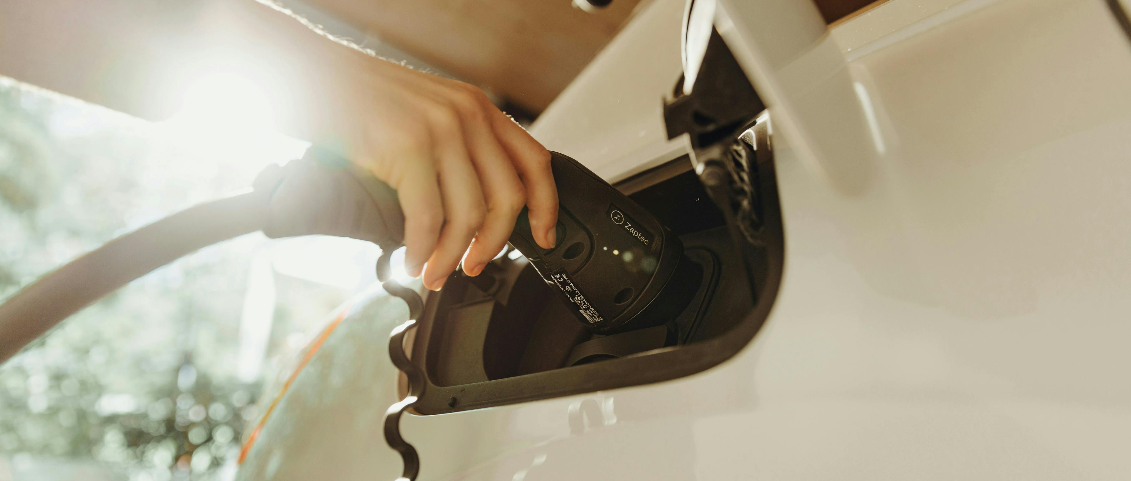 Hand holding charger to an EV port