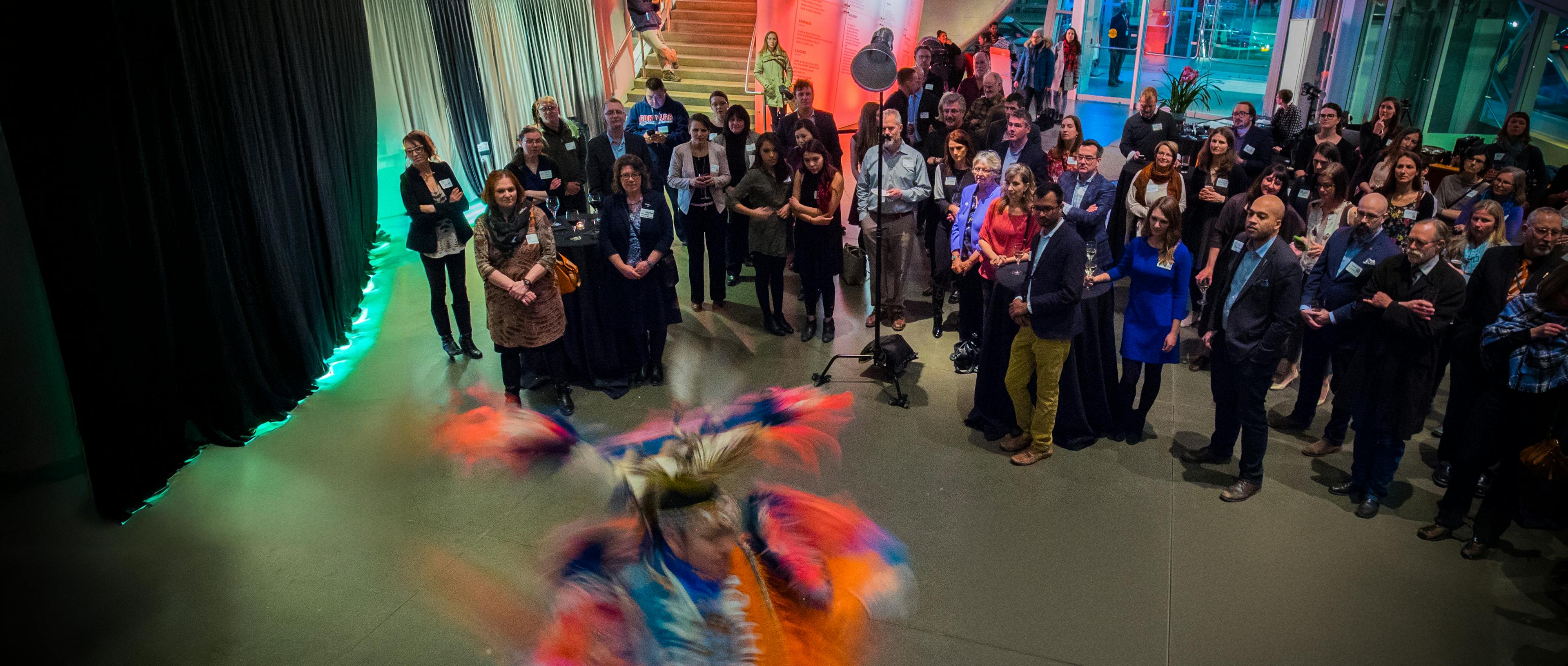 People at event watch an Indigenous dancer