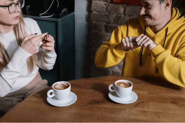 Two people conversing in sign language over coffee