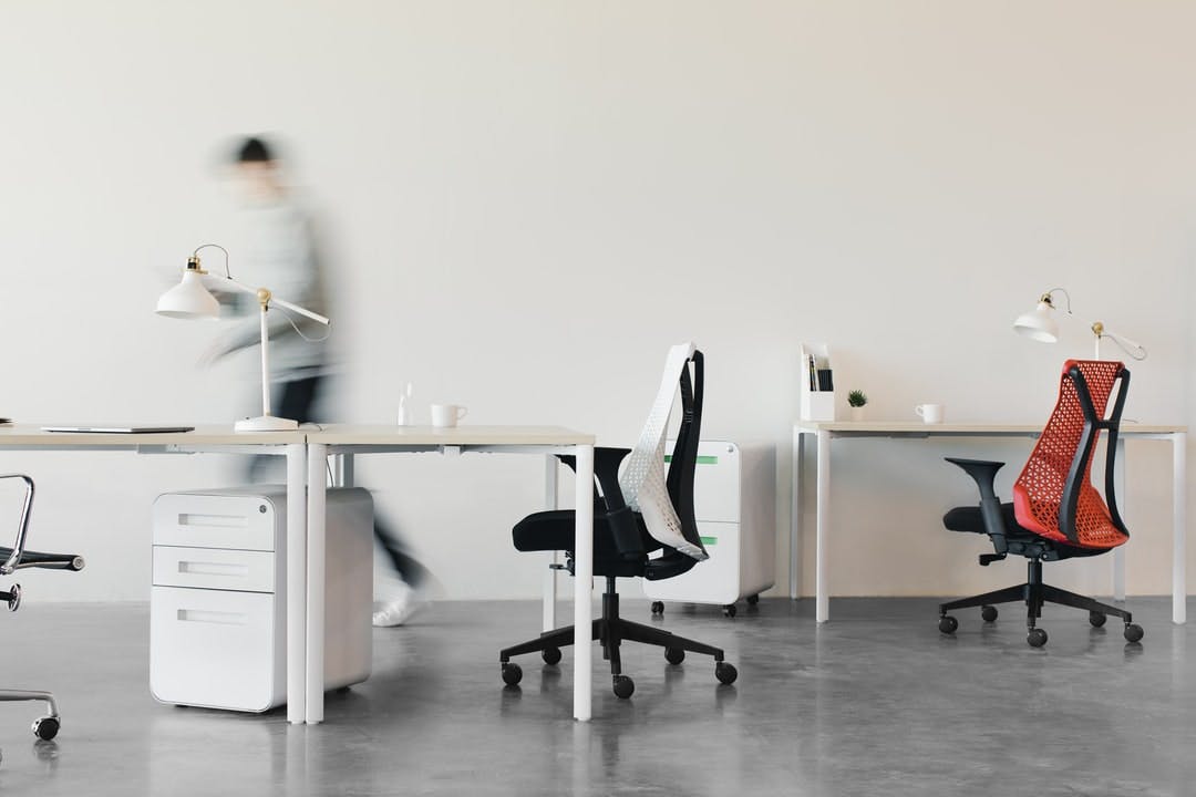 A person walking through a modern minimalist office of chairs and desks