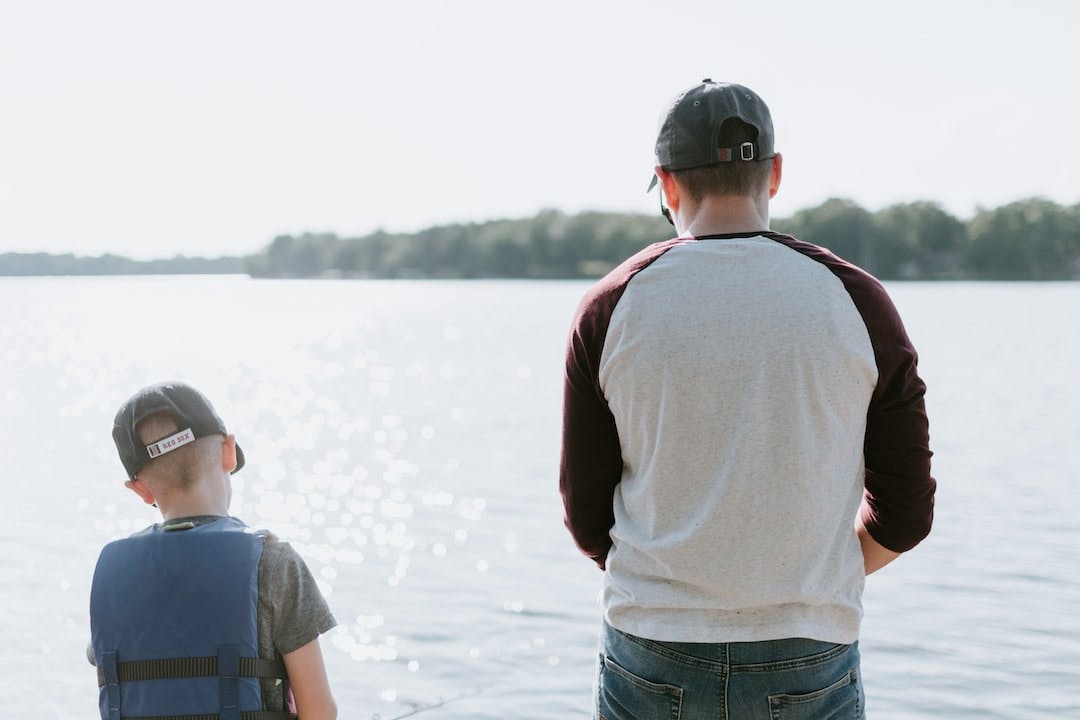 Father and son fishing both with Red Sox hats on 