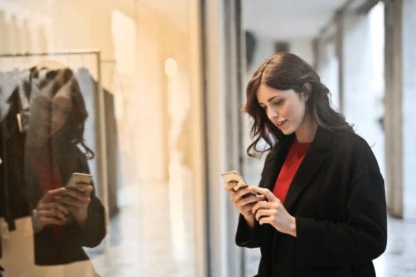 A retail worker taking mobile education by their storefront