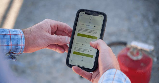 A man taking a mobile training course on his phone on the job.