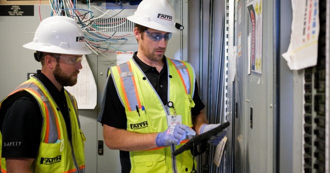 Two workers using an LMS on a tablet for compliance training.