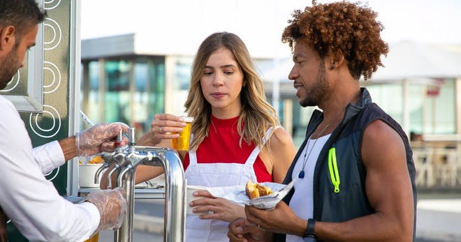 An alcohol server preparing drinks for two customers