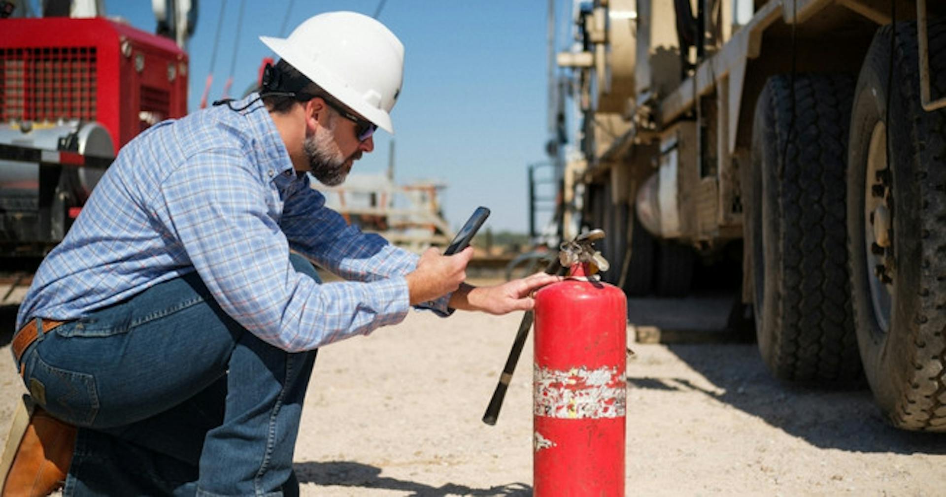 A worker using his phone to take a photo of a portable fire extinguisher 