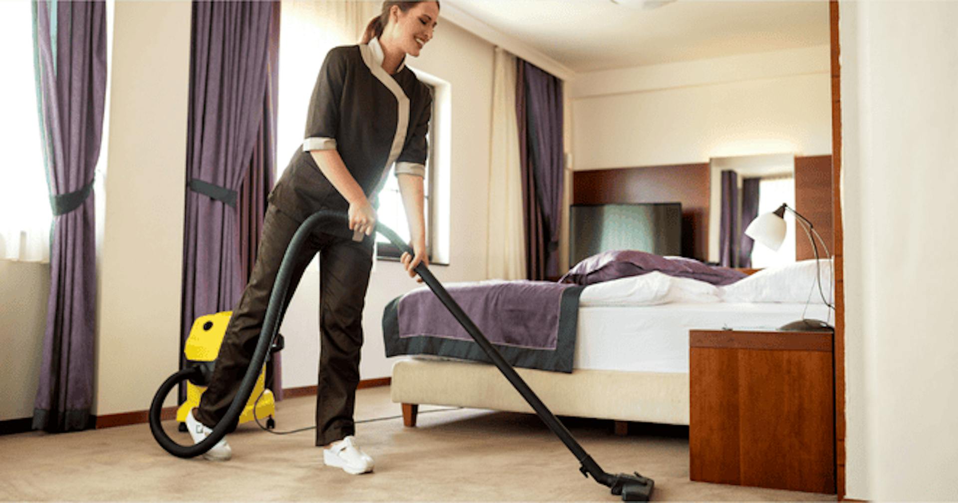 Housekeeping staff vacuuming hotel room floor