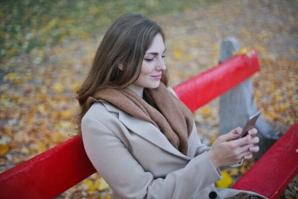 Woman on a park bench taking an online course on her mobile phone