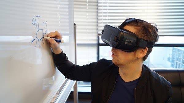 A person writing on a whiteboard with VR googles on