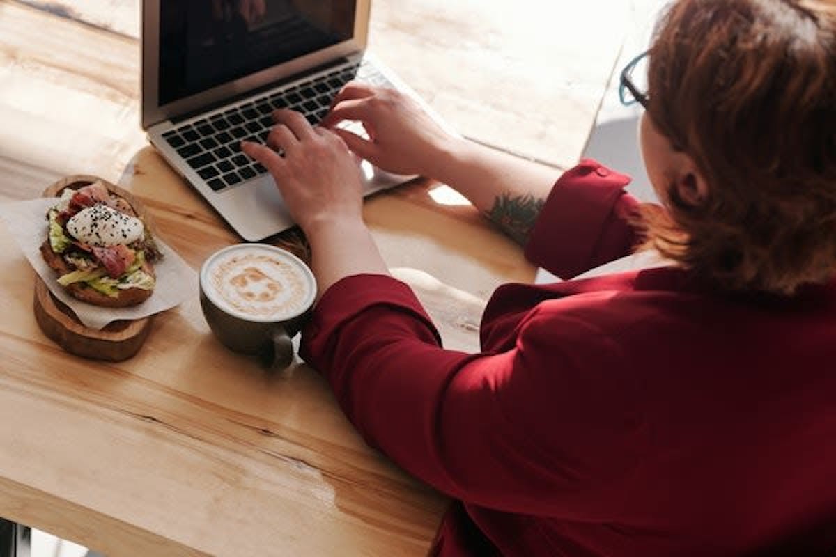 Woman working on her table working while eating and drinking coffee