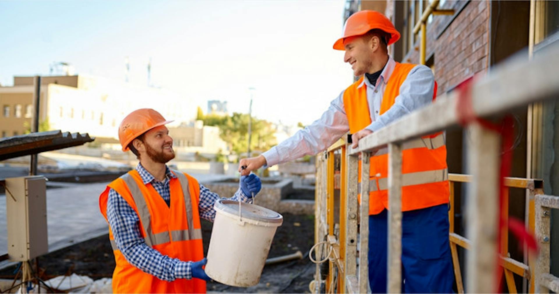 Two employees carrying materials out of the work site