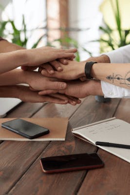 Team hands in over huddle table