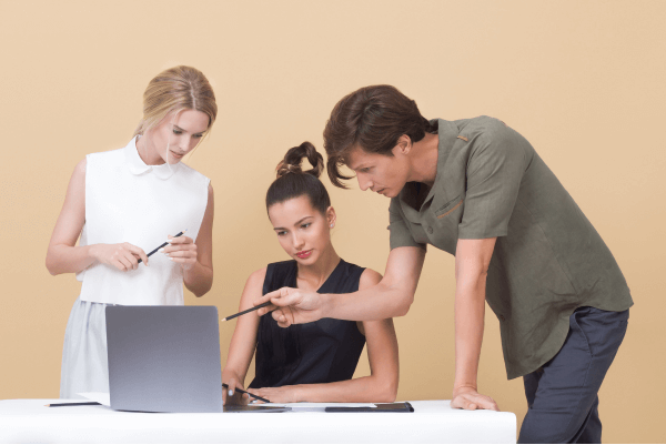 Workers providing constructive feedback in front of a laptop