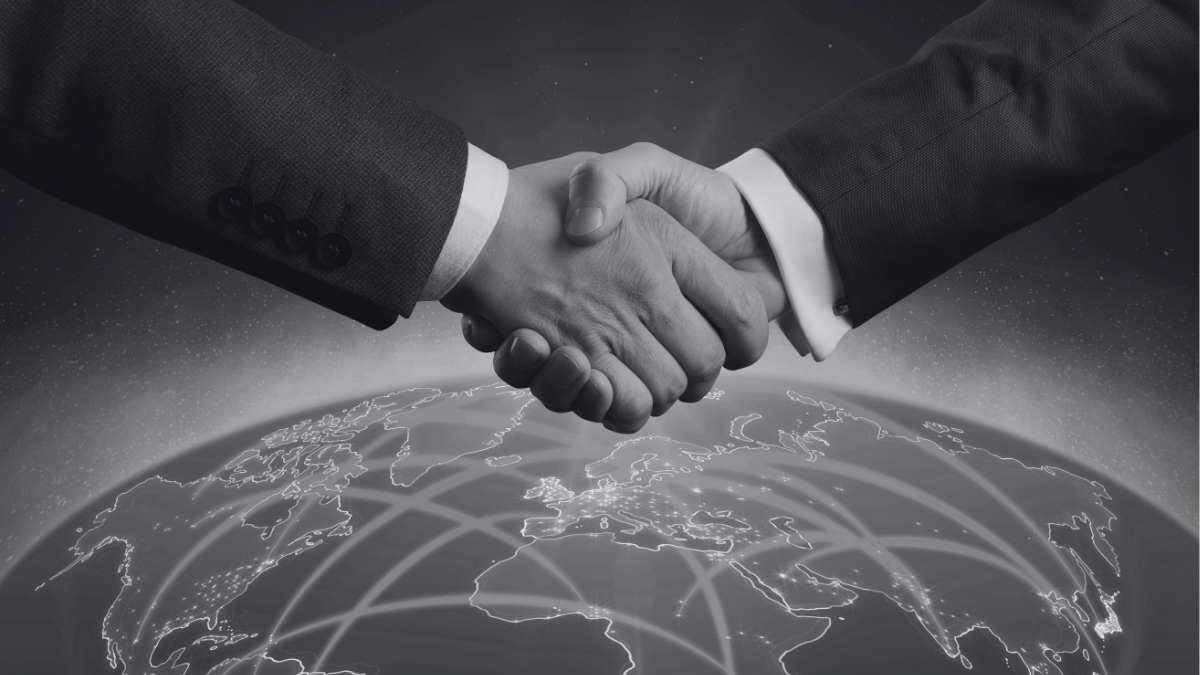 Two people shaking hands in front of a stylized world that shows global digital connections.