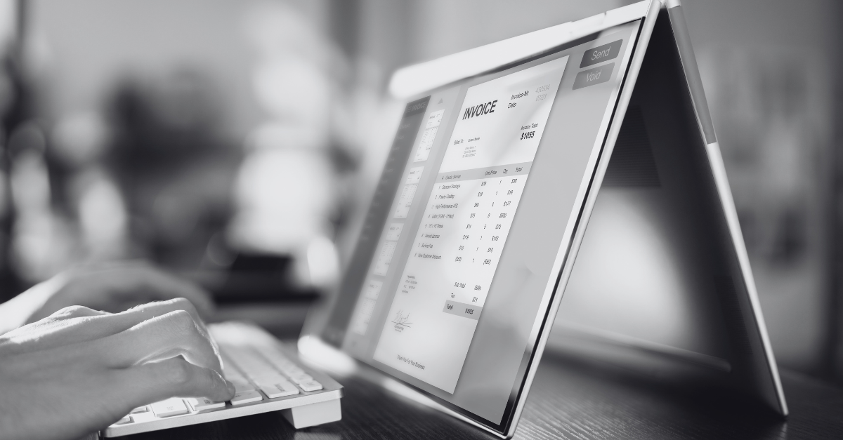 Eine Person tippt auf einer Tastatur, die an einen Laptop angeschlossen ist. Auf dem Bildschirm ist eine elektronische Rechnung zu sehen.