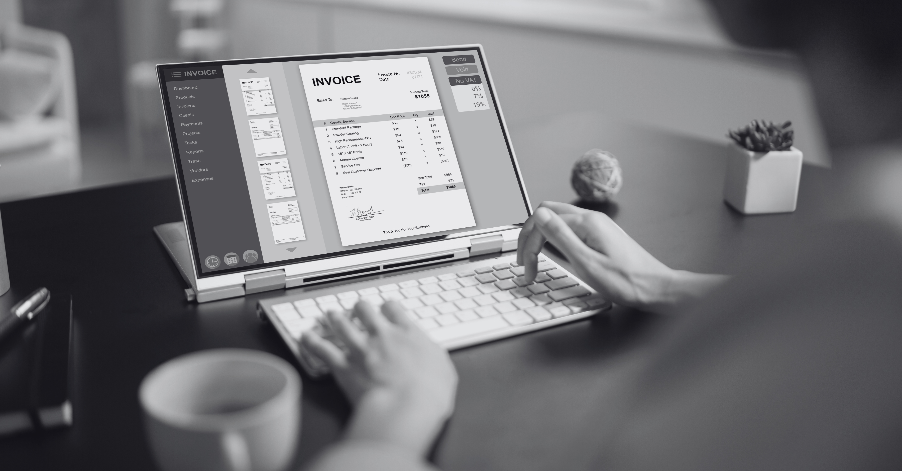 A person is working on a laptop with an external keyboard, viewing an electronic invoice on the screen. 