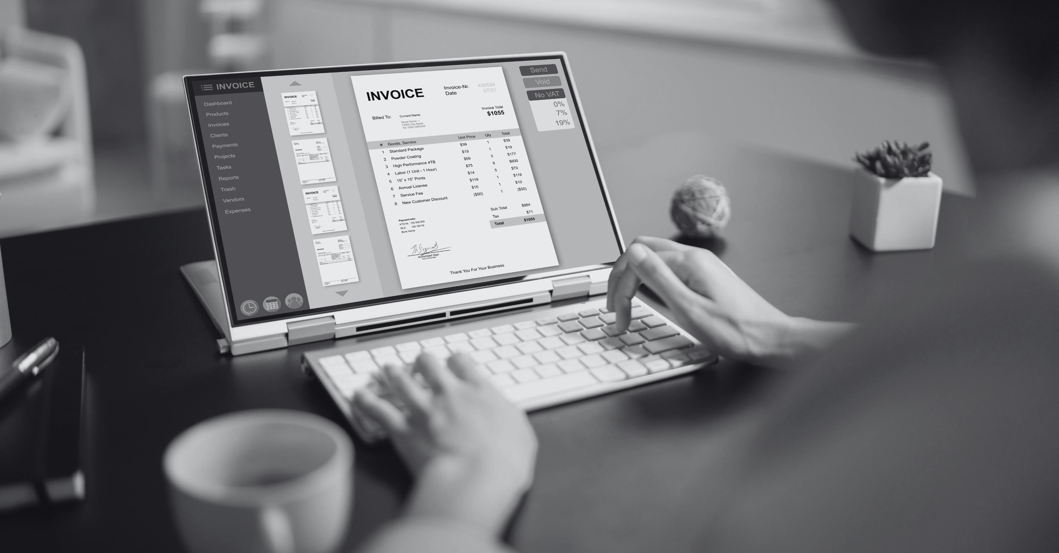 A person is working on a laptop with an external keyboard, viewing an electronic invoice on the screen.