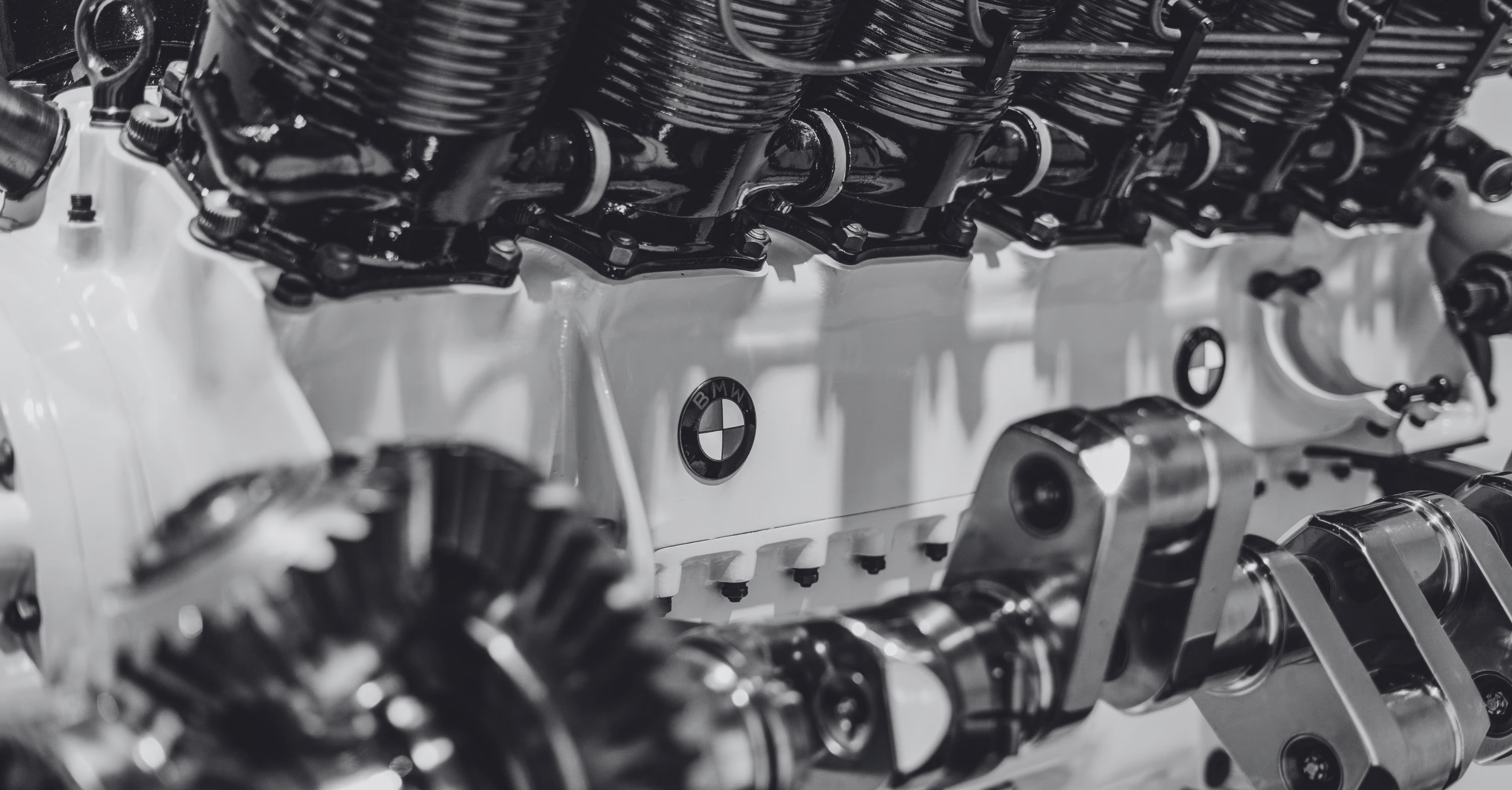 Close-up of a BMW engine, highlighting intricate parts, gears, and the BMW logo.