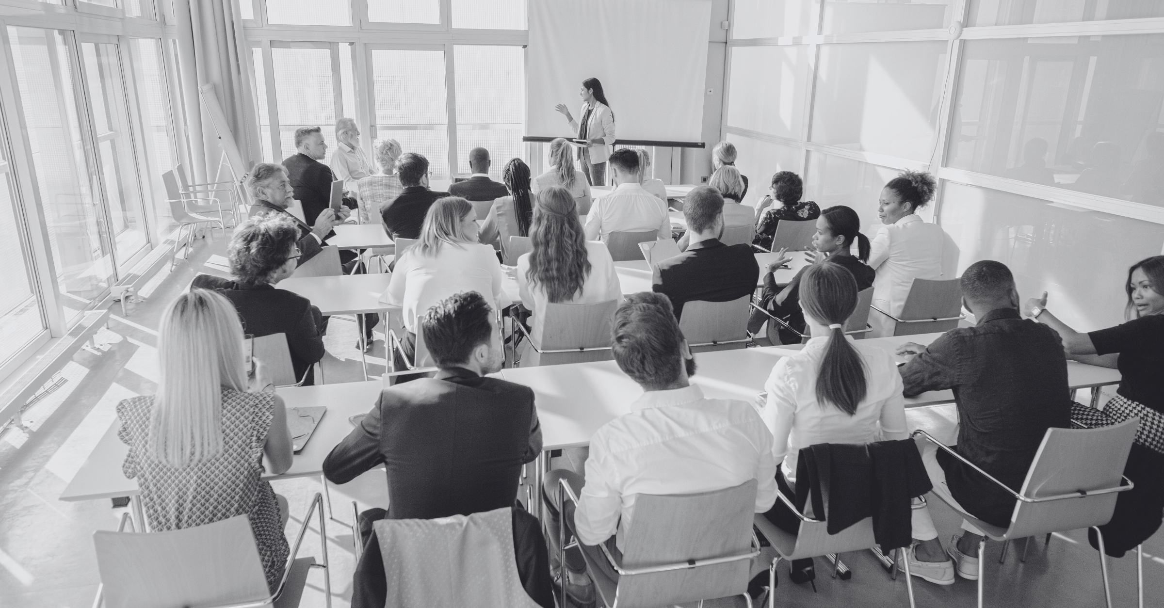 Ein Seminarraum, in dem eine Frau vor sitzenden Personen steht und spricht.