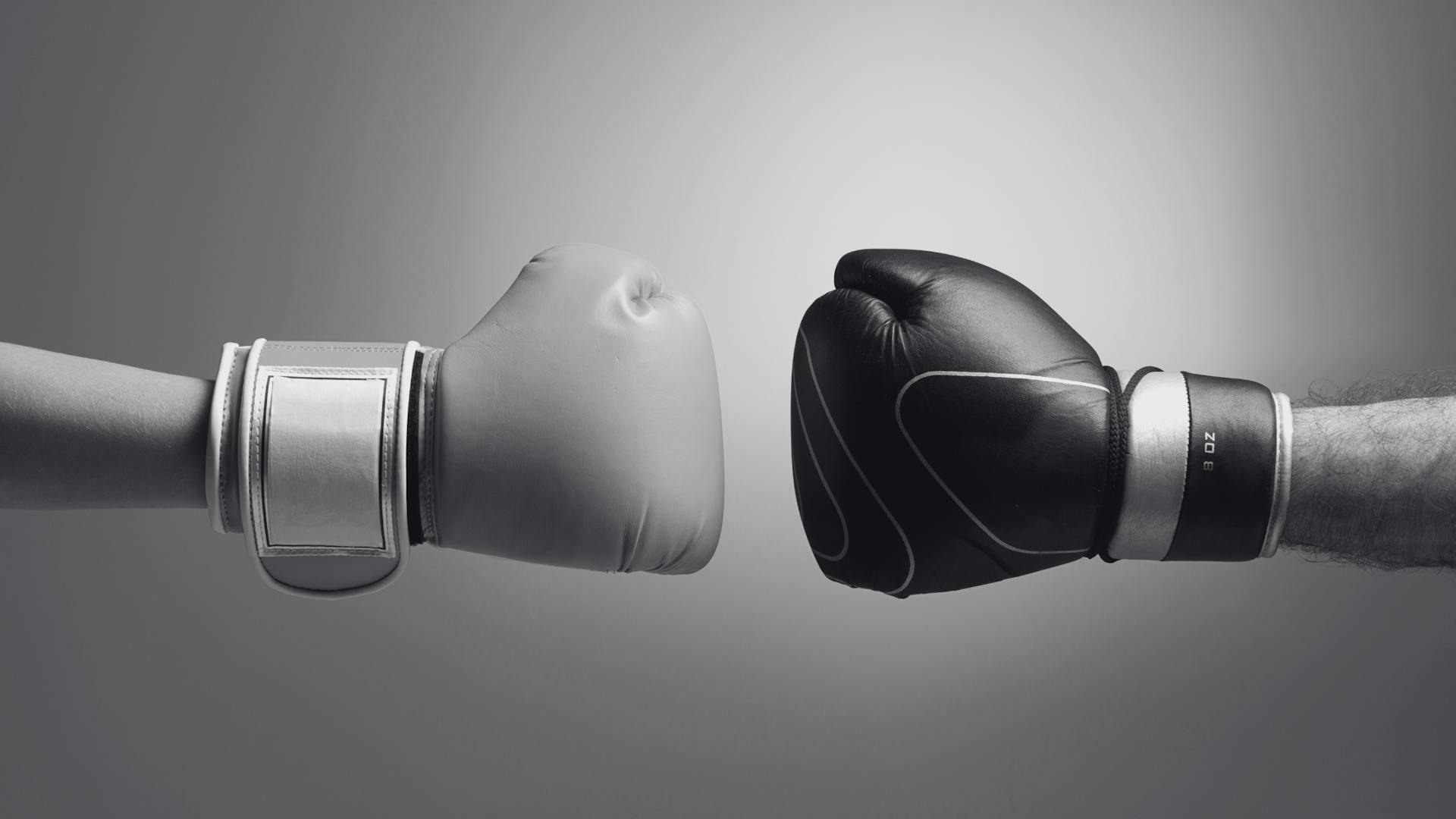 Two gloved hands symbolize the comparison or competition between two technologies or approaches in a boxing match. Two gloved hands symbolize the comparison or competition between two technologies or approaches in a boxing match.