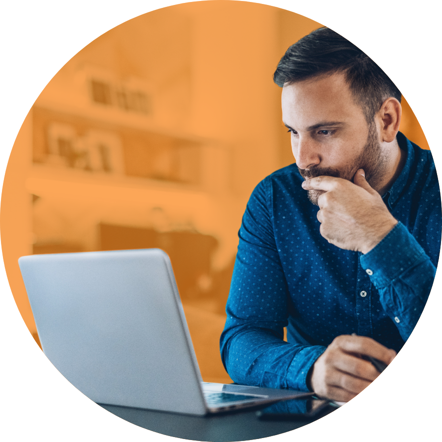 Rounded image of a frustrated person sitting at a desk, staring at a laptop screen.