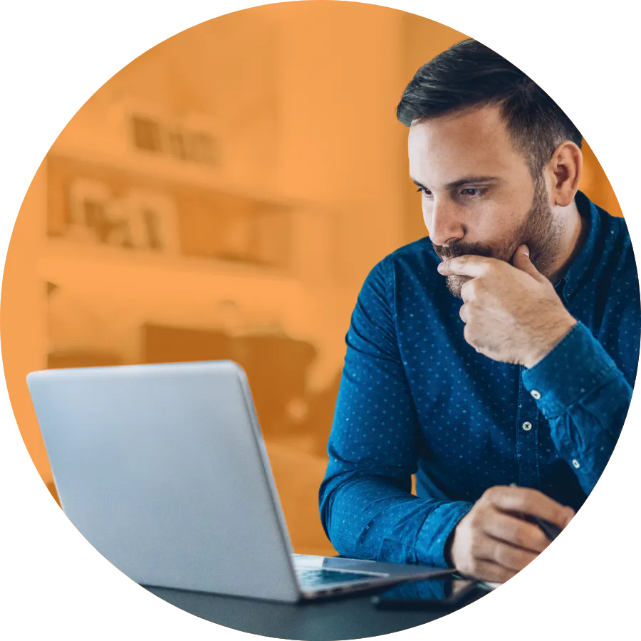 Rounded image of a frustrated person sitting at a desk, staring at a laptop screen.