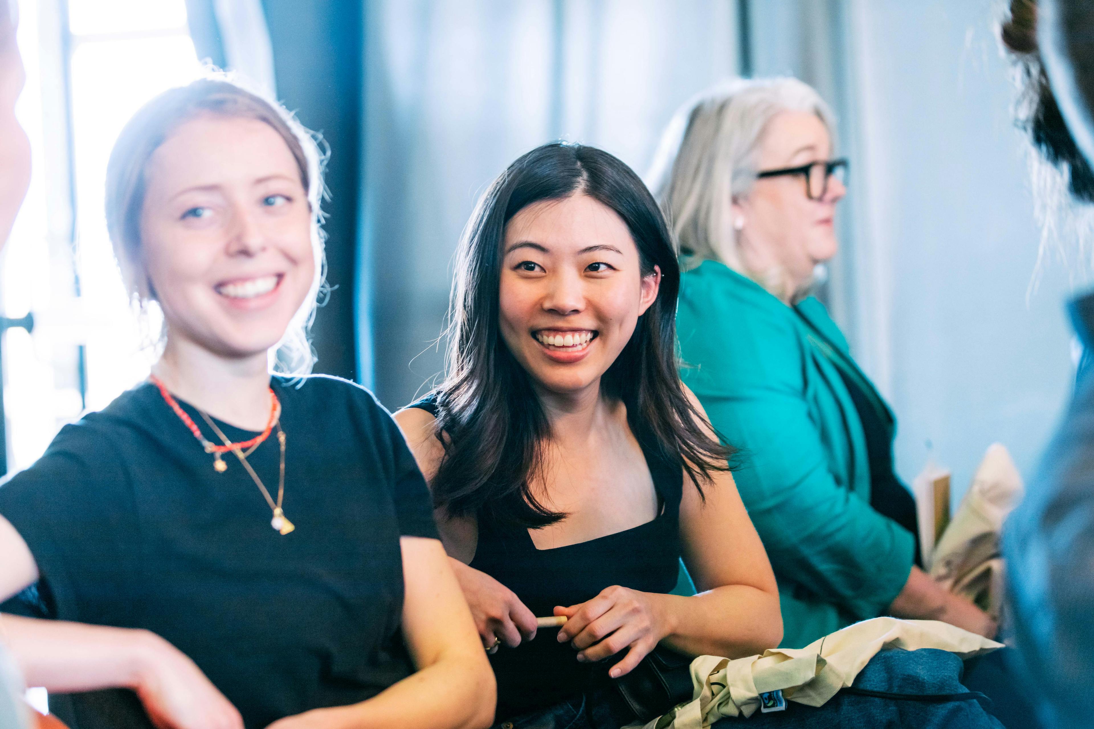 Diverse female employees smiling and collaborating together at a corporate event.