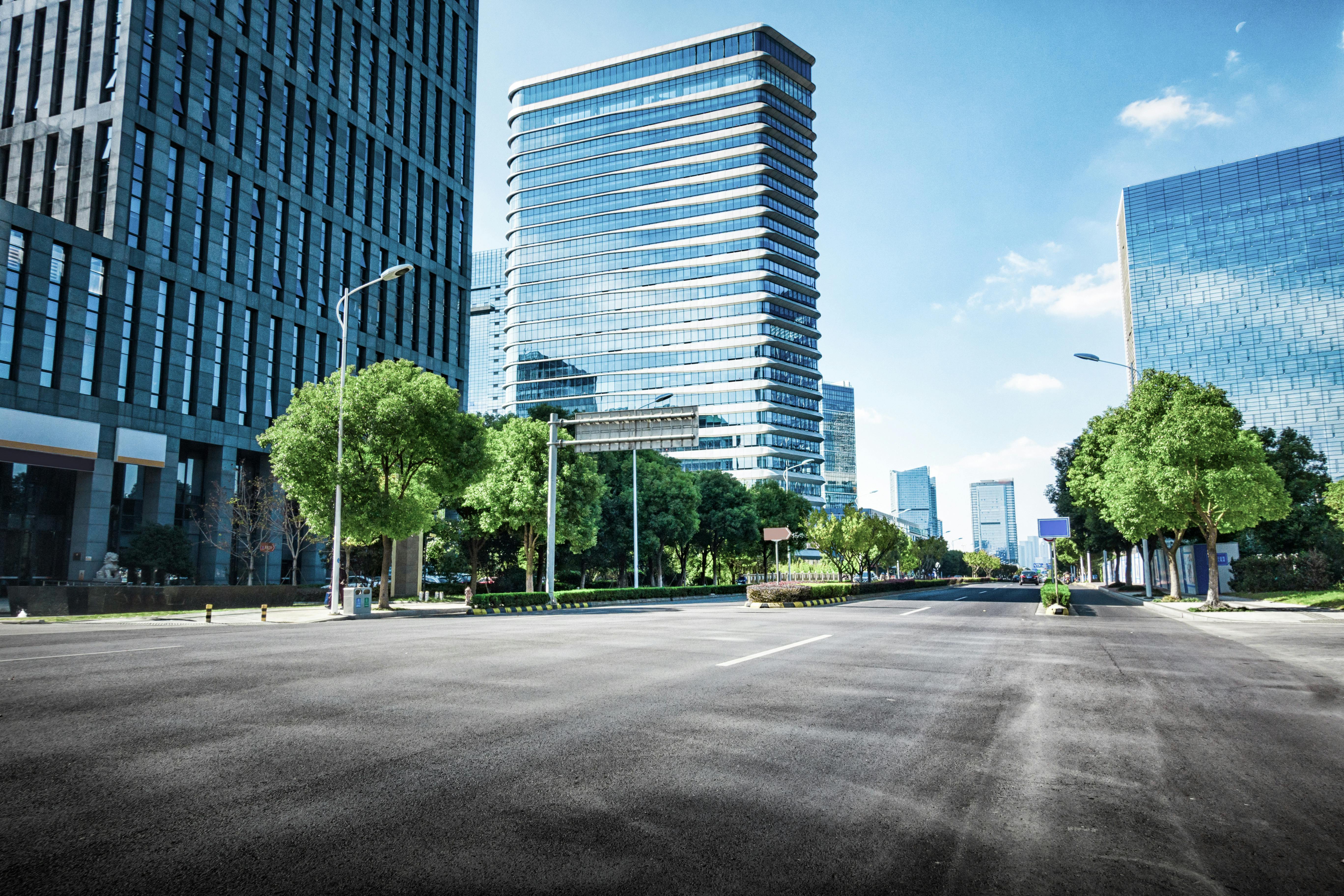 Buildings in the foreground with a large road, with lined trees showcasing the built environment.