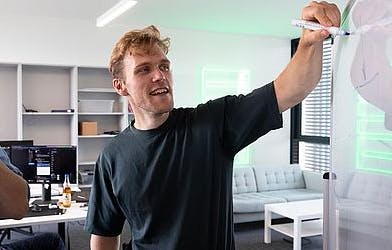 a guy writing on a whiteboard