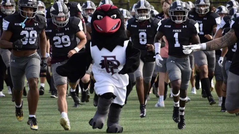 Franklin Pierce University Raven Mascot storms the field with the football team running behind