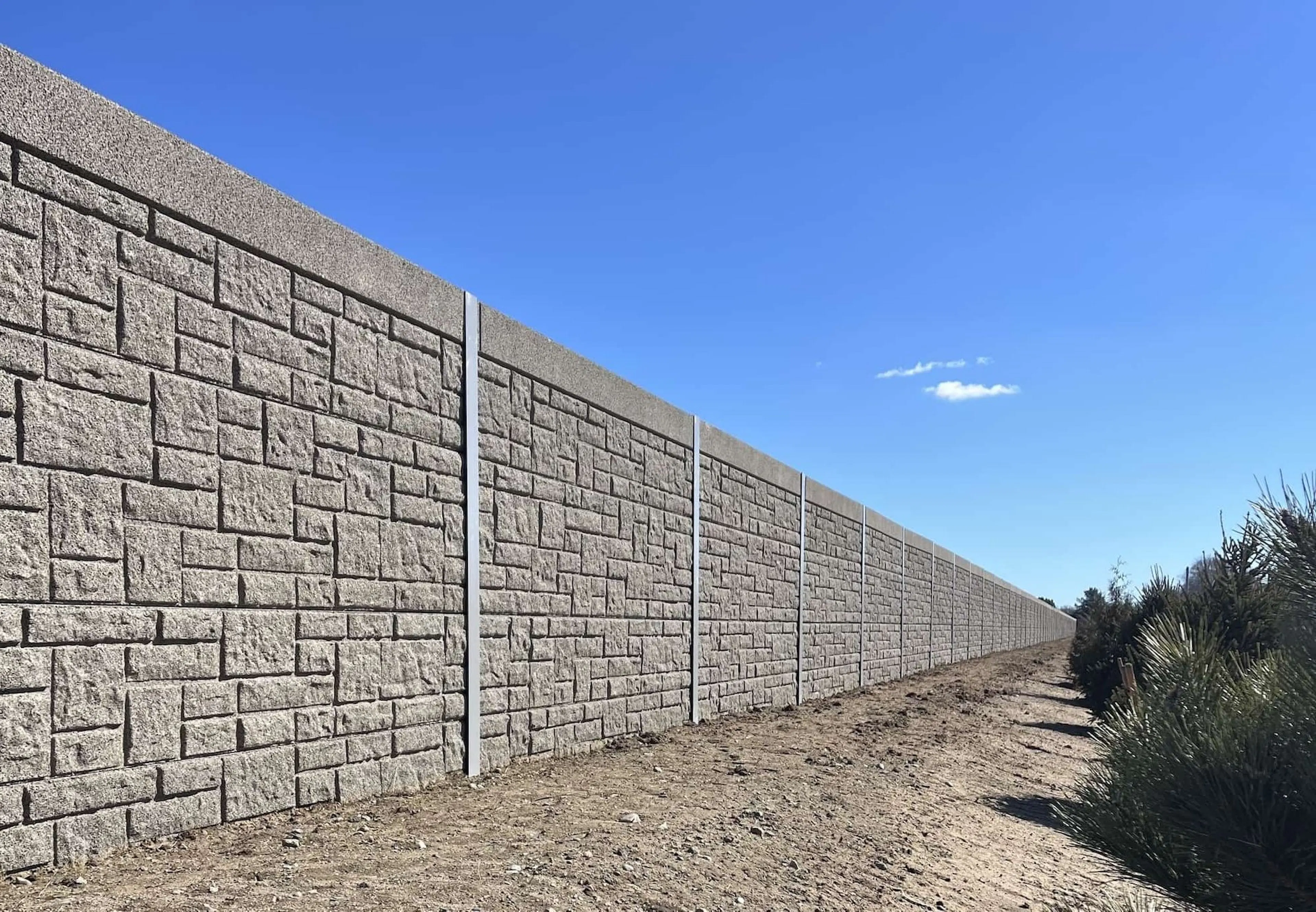 Stone-patterned sound wall running the length of the residential property line at TF Green Airport
