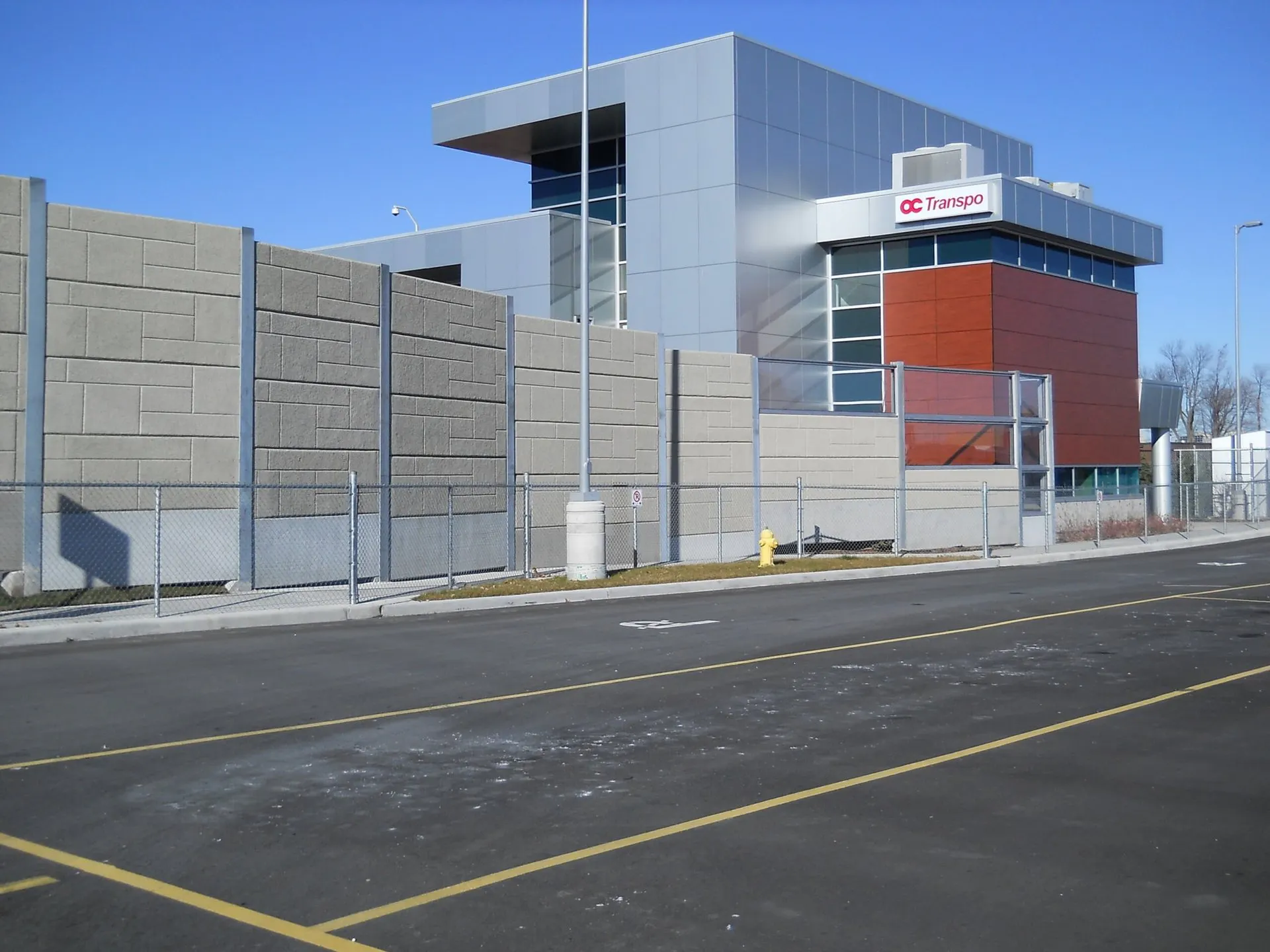 Absorptive noise wall running along the roadway in front of the OC Transpo maintenance building