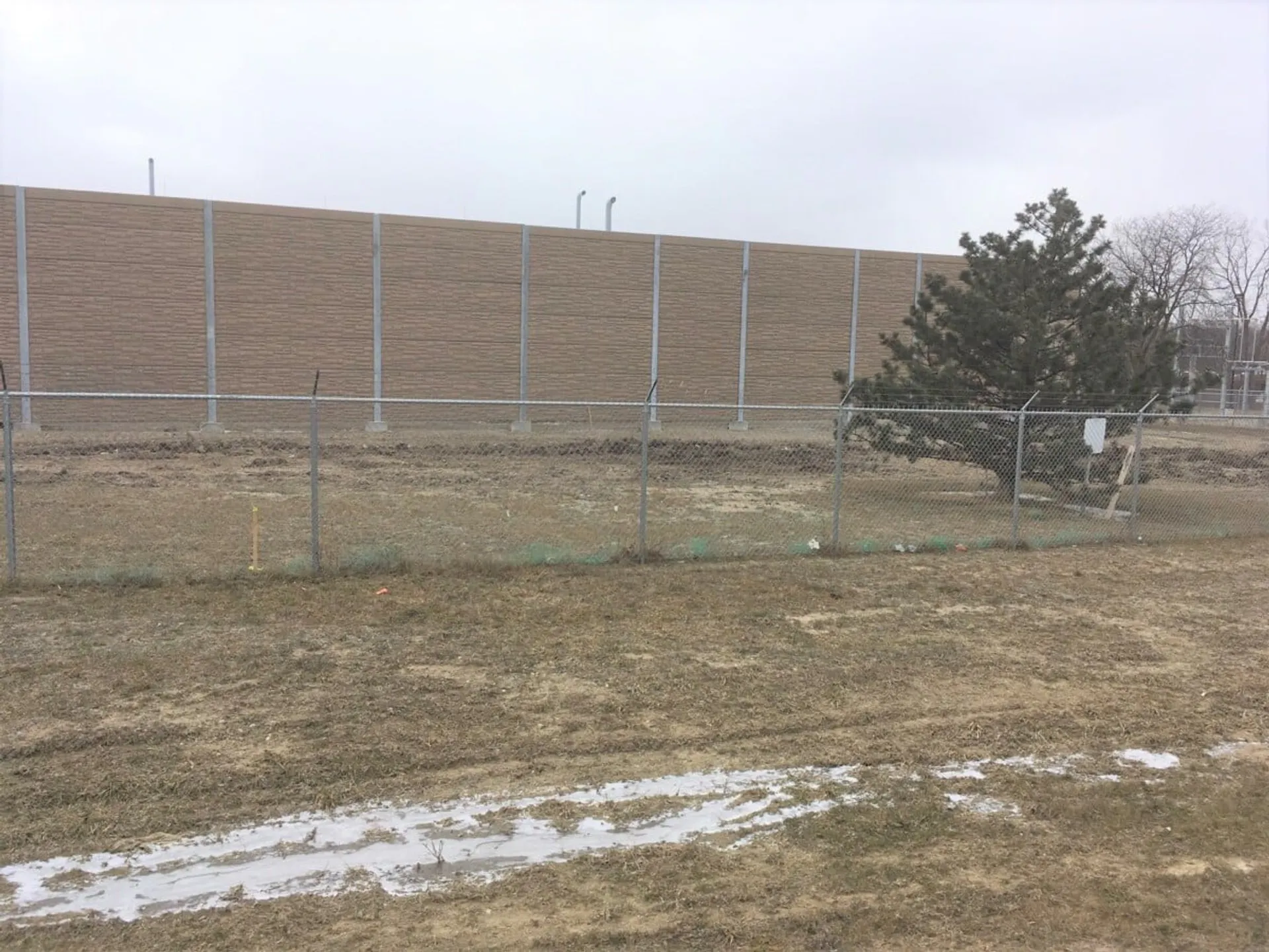 Noise wall seen across the field from the property line, screening the landfill gas equipment from neighbours