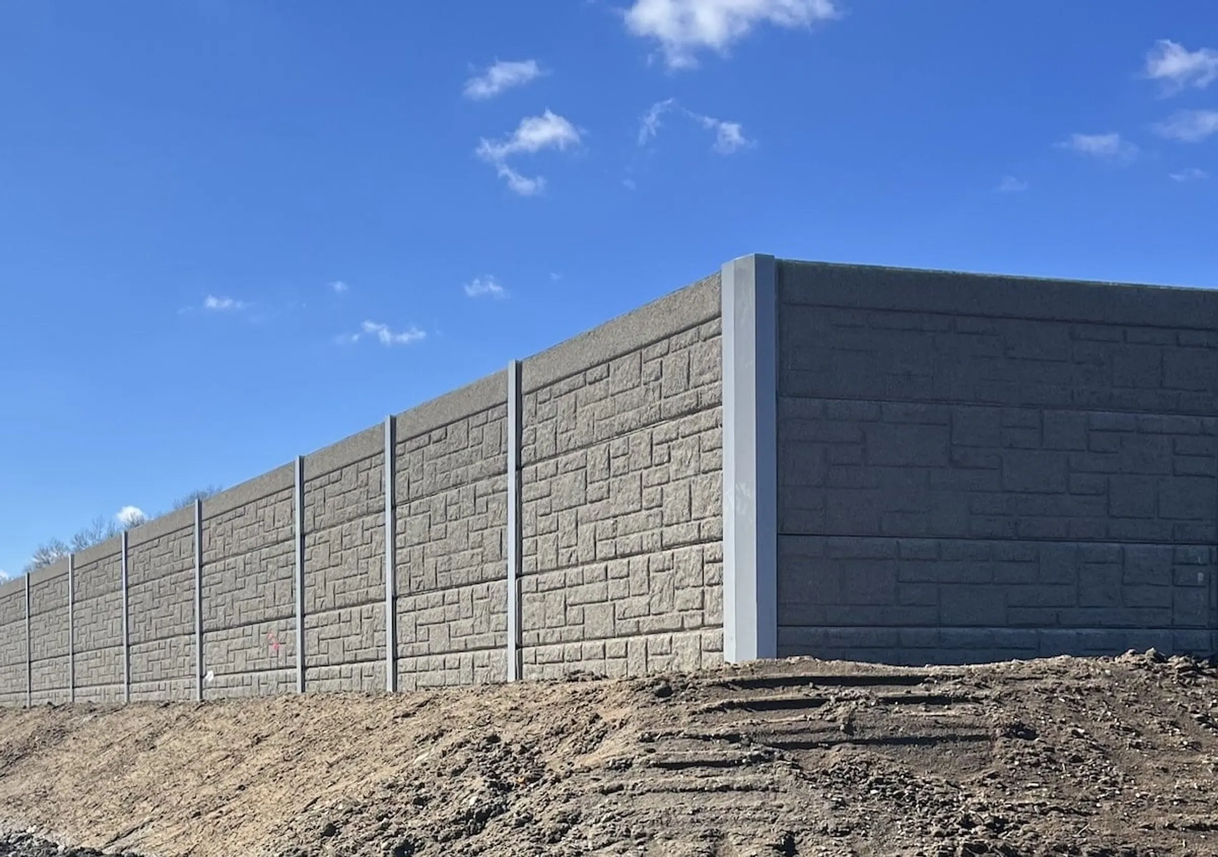 Dark grey precast sound wall turning a corner at TF Green Airport above freshly graded soil