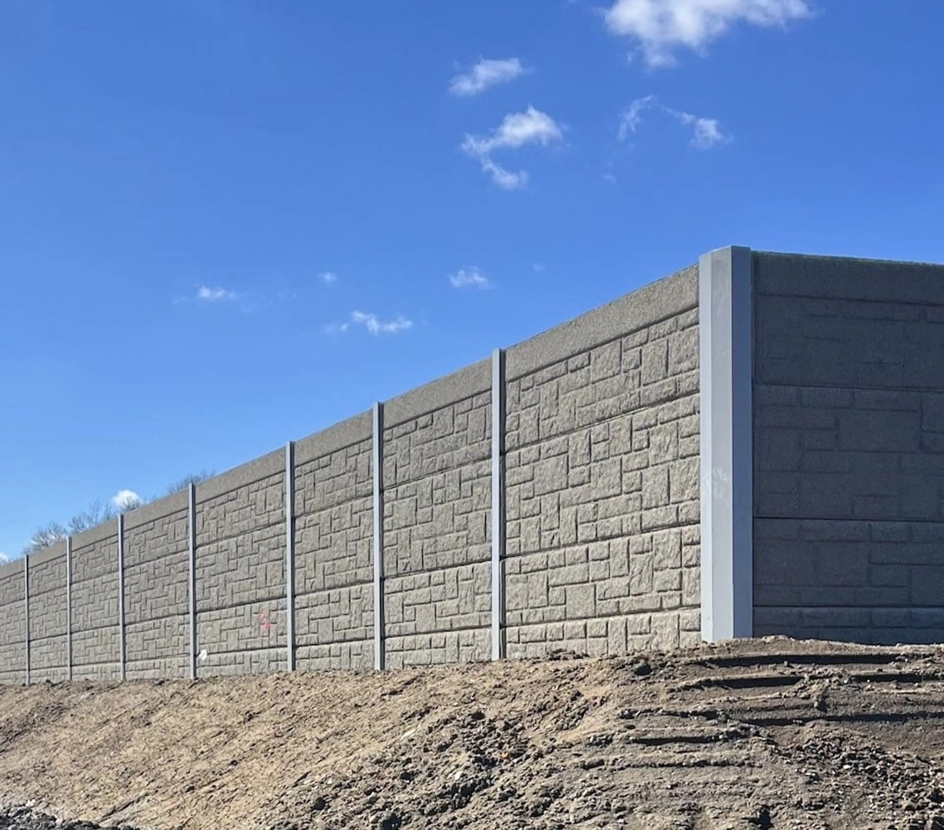 Dark grey precast sound wall turning a corner at TF Green Airport above freshly graded soil