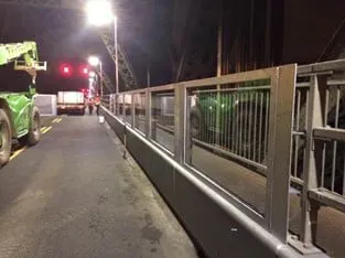 New barrier with transparent panels running the length of the Pont de Quebec deck under floodlights at night