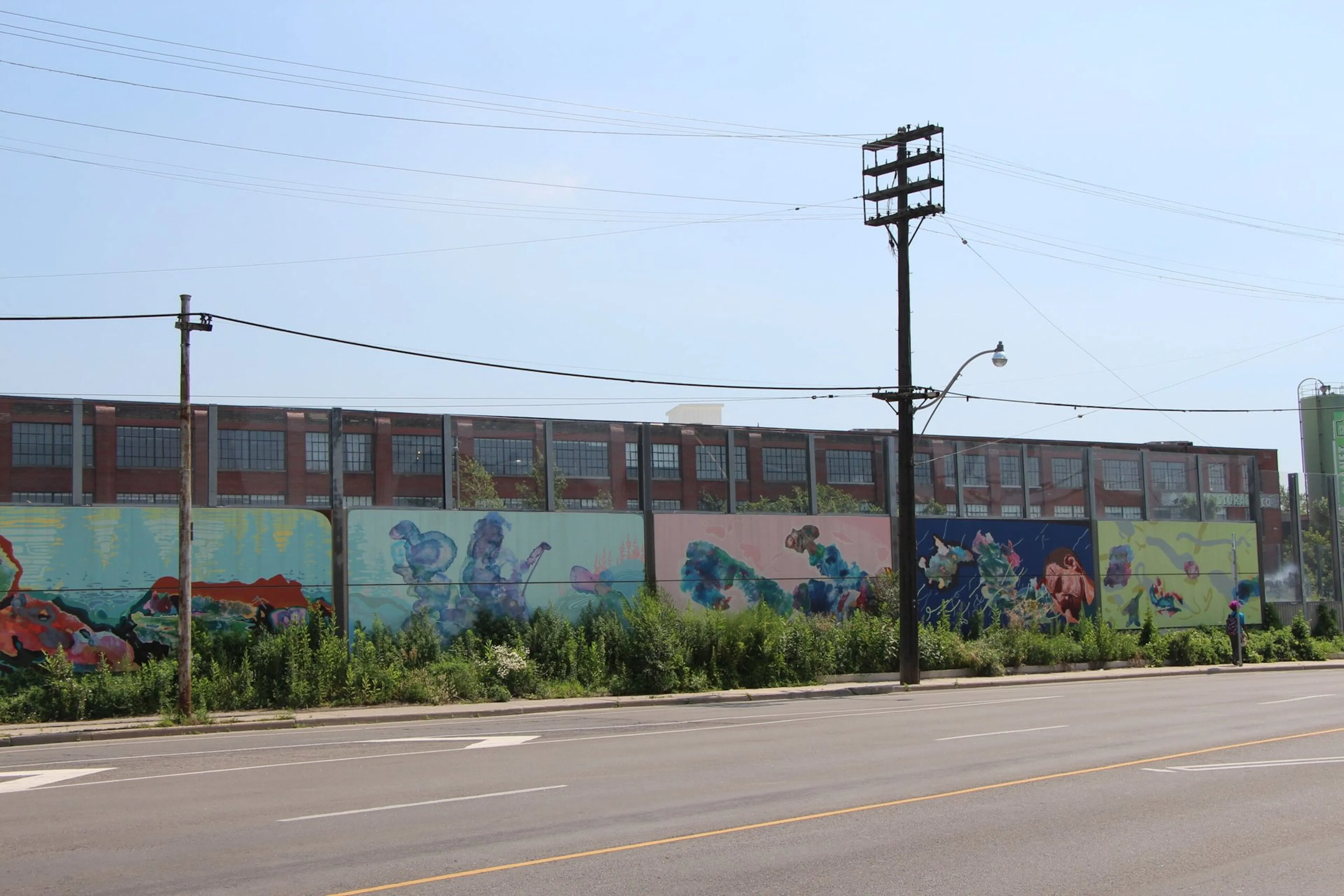 Community murals painted along the street-facing side of the UP Express noise wall
