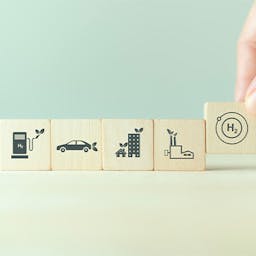 Des cubes en bois avec des icônes de pompe, voiture, immeuble, usine et d'hydrogène vert