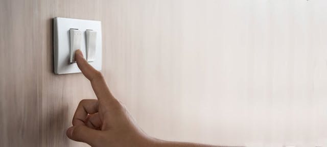 Une main appuyant sur interrupteur pour faire des économies d’électricité.