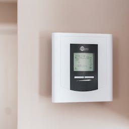 Thermostat connecté posé sur un mur beige