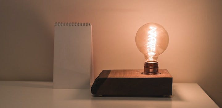 Une ampoule sur un bloc avec un carnet vide à côté