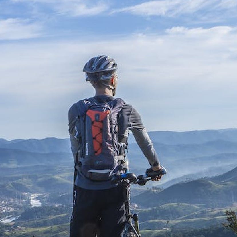 Un homme tenant son vélo éléctrique et regardant le paysage.