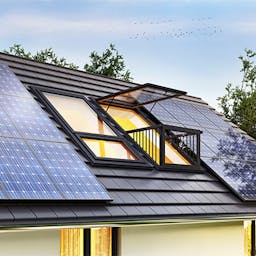 Toit d'une maison recouvert de panneaux solaires et deux deux balcons, dont un avec la fenêtre ouverte 