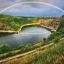 Arc-en-ciel sur un lac entouré de de collines