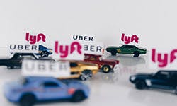 Petites voitures avec des pancartes Lyft ou Uber sur le capot.