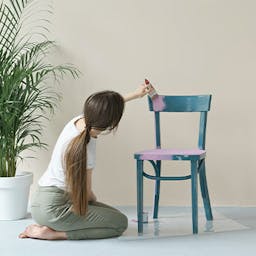 Une femme qui redonne une seconde vie à une chaise pour son déménagement en la peignant
